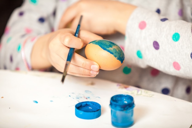 Gros plan d'une fille tenant un pinceau et peignant des œufs d'ester