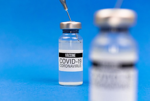 Gros plan sur les flacons de vaccin, se préparant à la vaccination contre le COVID-19, photo d'arrière-plan bleu