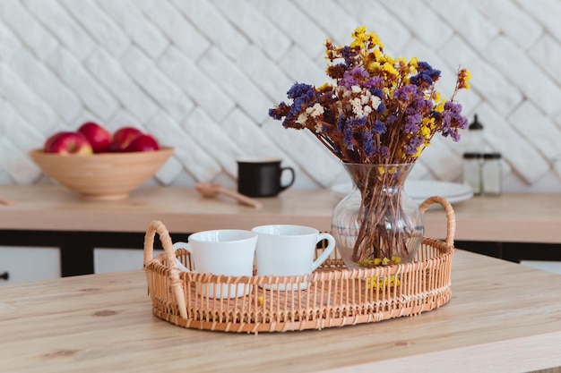 Gros plan de fleurs sèches debout sur la table en bois avec deux tasses de thé ou de café