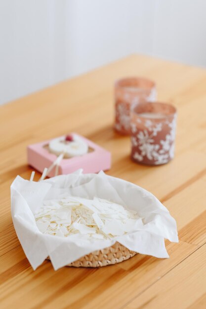 Gros plan de flocons de cire de soja blanc pour faire des bougies dans un panier en osier sur une table en bois