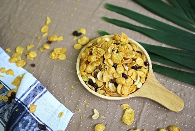 Gros plan sur des flocons de maïs au caramel au miel avec des raisins secs et des noix de cajou sur une plaque de bois