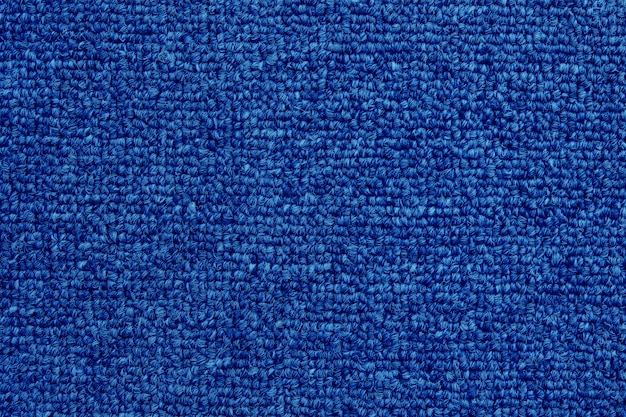Gros plan de fond de texture de tapis de couleur bleu foncé avec motif sans soudure.