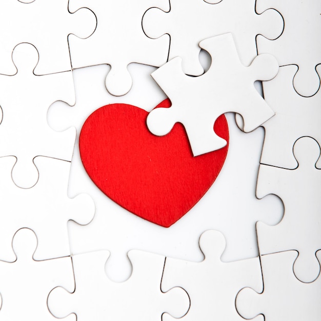 Photo un gros plan de la forme d'un cœur au milieu d'un puzzle blanc sur la table