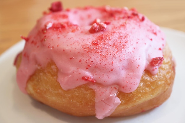 Gros plan d'une fraise alléchante glacée avec un beignet de remplissage à la crème de framboise