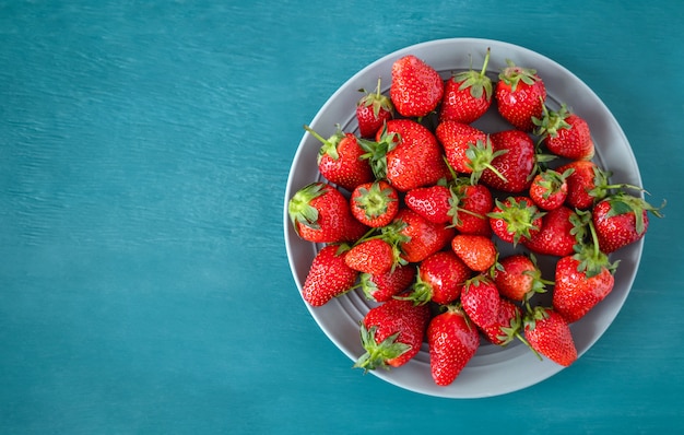 Gros plan d'une fraise fraîche dans un bol sur fond bleu clair