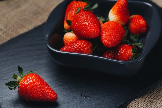 Gros plan de fraises lavées dans un tamis avec trois fraises fraîches et juteuses