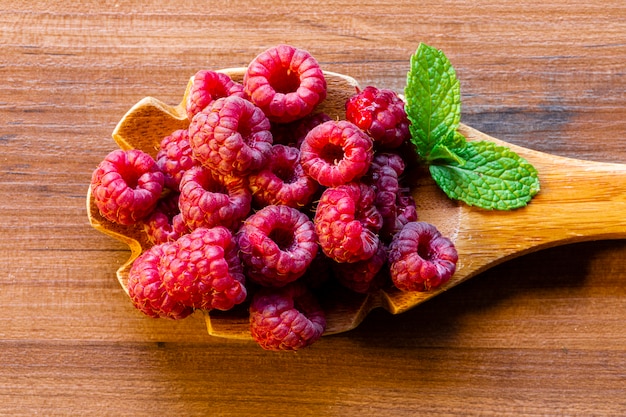 Gros plan sur les framboises dans une cuillère en bois sur fond rustique