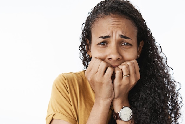 Photo gros plan de freakedout bouleversé pleurer femme afro-américaine effrayée et terrifiée tremblant de peur se ronger les ongles et froncer les sourcils paniquer ne peut pas se calmer sur fond gris