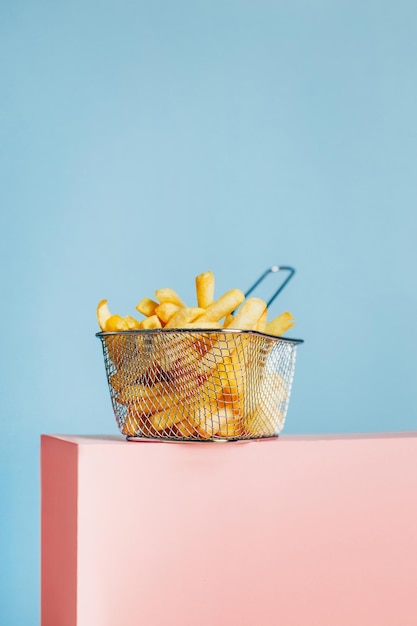 Gros plan de frites dans un panier sur un cube rose sur fond bleu avec espace libre pour le texte