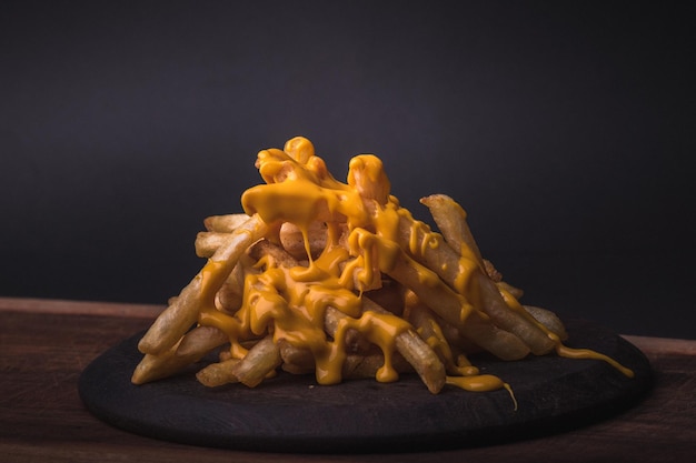 Gros plan de frites fraîches avec du fromage fondu sur une planche sur la table