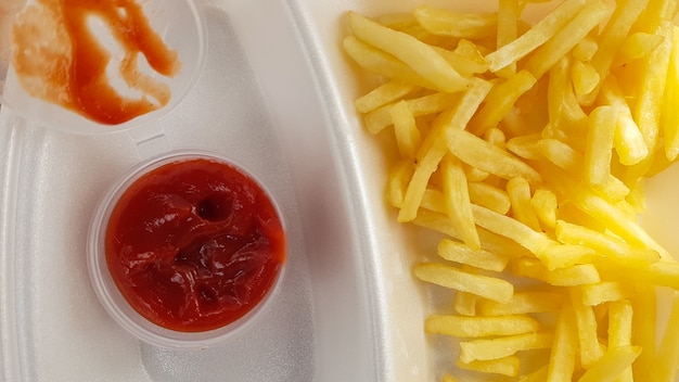 Un gros plan de frites jaune orangé doré avec du ketchup à la tomate