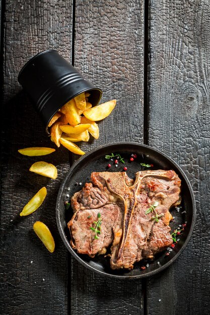 Gros plan de frites et steak tbone sur la table brûlée