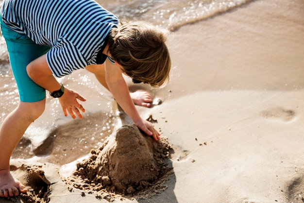 Gros plan d&#39;un garçon caucasien jouant avec le sable à la plage