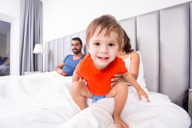 Gros plan sur un garçon drôle jouant au lit avec sa famille