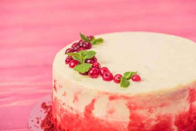 Gros plan sur un gâteau blanc décoré de groseilles rouges et de feuilles de menthe