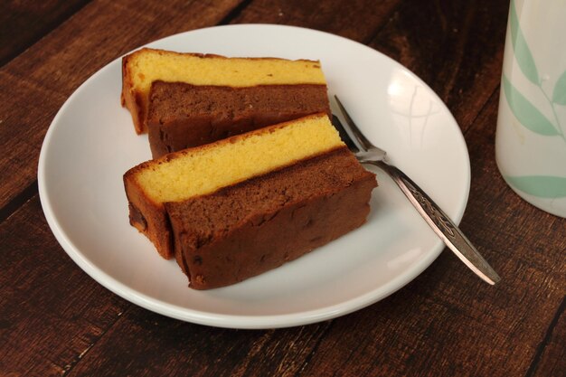 Gros plan sur un gâteau en couches au chocolat et à la vanille sur une plaque blanche