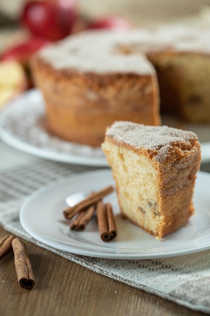 Gros plan d'un gâteau éponge ou d'un gâteau en mousseline de soie avec des pommes si douces et délicieuses tranchées avec des ingrédients des œufs à la cannelle des pommes de farine sur une table en bois Concept de boulangerie maison pour le fond et le papier peint