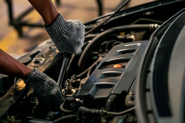 Photo gros plan, les gens réparent une voiture utilisez une clé et un tournevis pour travailler dans un garage.