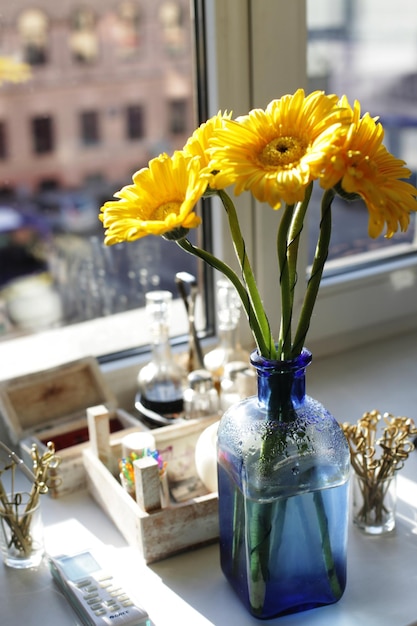 Gros plan de gerberas jaunes dans un petit vase bleu