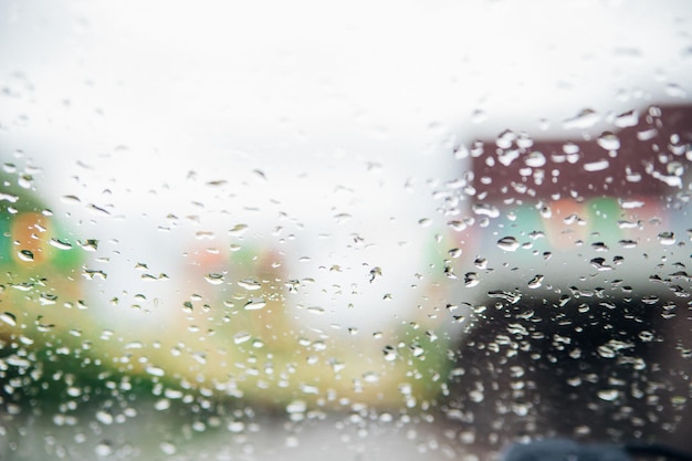 Gros plan de gouttes de pluie sur verre transparentArrière-plan flou du paysage de silhouetteLa texture du verre humide Arrière-plan abstrait