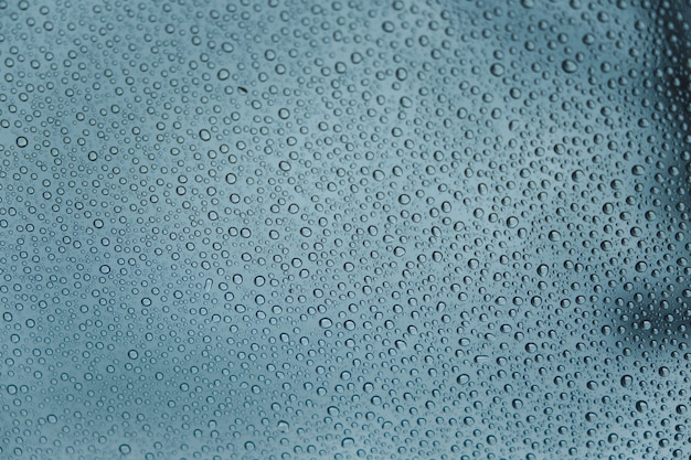 Gros plan de gouttes de pluie sur une vitre de voiture dans une journée nuageuse de l'intérieur de la voiture