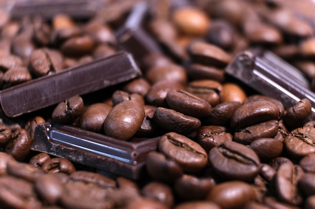 Gros plan des grains de café aromatiques torréfiés foncés et fond de chocolat