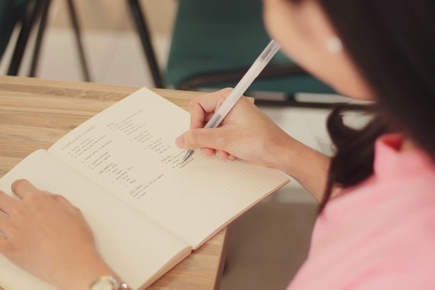 Gros plan grand angle d'une femme prenant des notes dans un cahier