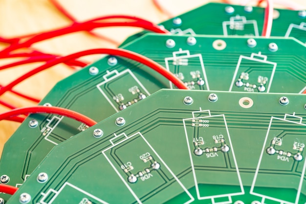 Gros Plan Sur Un Grand Microcircuit Vert Avec Des Fils Rouges à Haute Tension Et Des Relais Bleus Qui Y Sont Connectés Dans Une Usine D'équipement Militaire. Le Concept De Nouvelles Technologies Haute Tension En Production