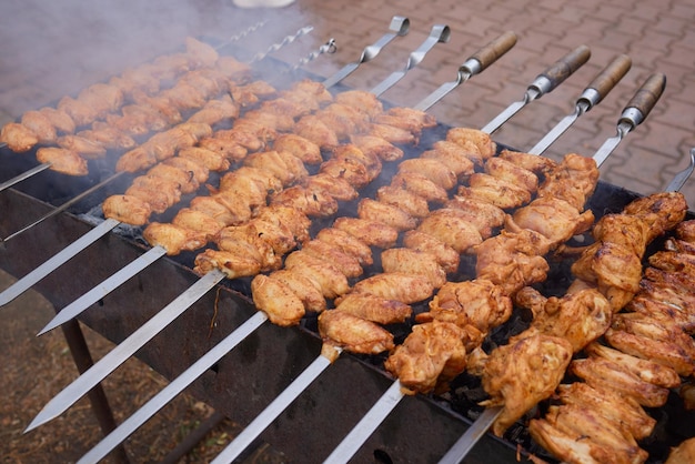 Gros plan d'une grande dinde marinée ou d'un steak de viande de poulet shashlik ou shish kebab préparant la cuisson sur un barbecue brazier grill sur charbon de bois sur charbon brûlant Brochettes rôties sur barbecue