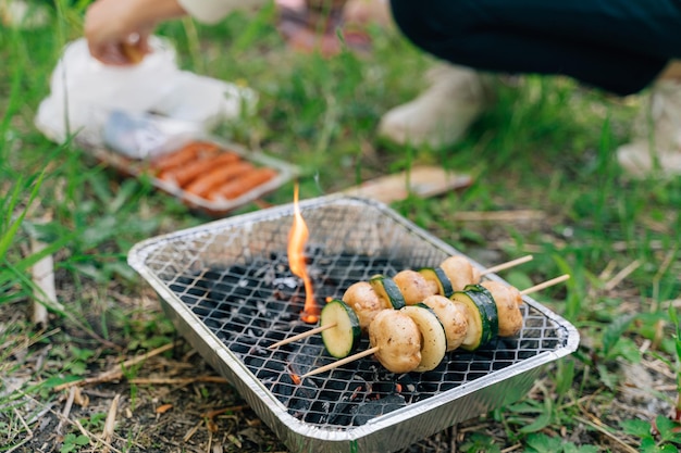 Gros plan sur un gril à usage unique pour un pique-nique en plein air avec des légumes sur un bâton en bois