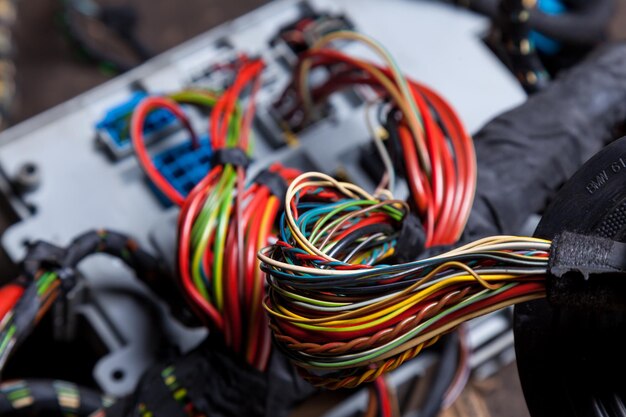 Photo gros plan d'un gros câble d'une bobine de fils de différentes couleurs de nuances colorées entrelacés et reliés par une isolation noire câblage internet d'un réseau électrique fournissant du travail à domicile
