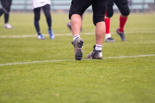 gros plan d'un groupe de jeunes joueurs professionnels de football américain s'échauffant et s'étirant ensemble avant une pratique sur le terrain se concentrer sur les jambes