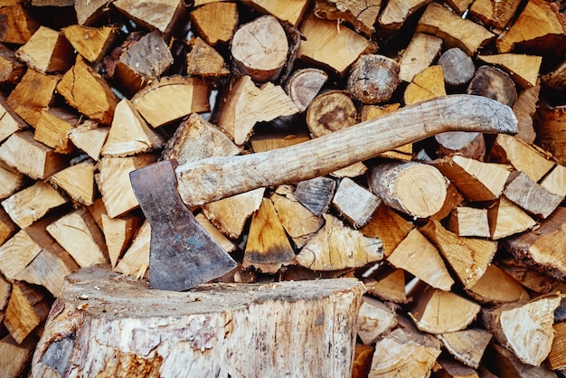 Gros plan d'une hache contre fond de bois de chauffage