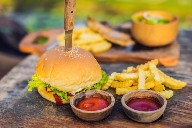 Gros plan d'un hamburger frais avec des frites sur une table en bois avec des bols de sauce tomate. nourriture de style de vie.