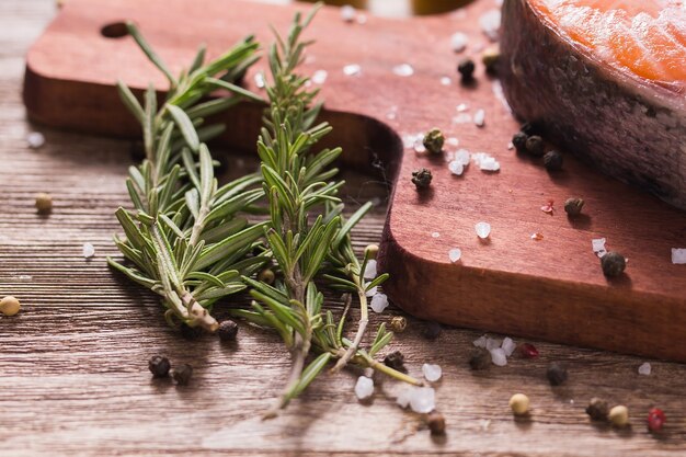 Gros plan d'herbes de romarin sur fond de planche à découper.