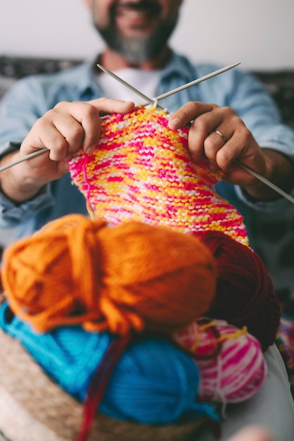 Gros plan sur un homme adulte travaillant avec un fil de balle de laine colorée. Des gens heureux dans les loisirs d'intérieur utilisant de la laine et faisant du tricot. Activité de loisirs d'intérieur