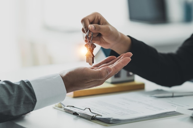 Gros plan Homme d'affaires ou agent immobilier donnant la clé de la maison après la signature d'un accord pour l'achat d'une maison Gestionnaire de banque et concept immobilier