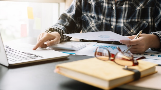 Gros plan d'homme d'affaires à l'aide d'une calculatrice et d'un ordinateur portable pour calculer les finances, les impôts, la comptabilité, les statistiques et le concept de recherche analytique