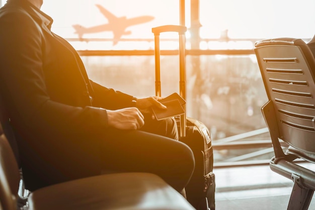 Gros plan sur un homme d'affaires assis avec un passeport en attendant de s'enregistrer pour embarquer avec des bagages à l'aéroport.