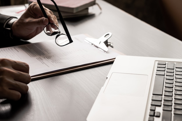 Gros plan d&#39;homme d&#39;affaires détenant des lunettes et de lire des documents sur le bureau.