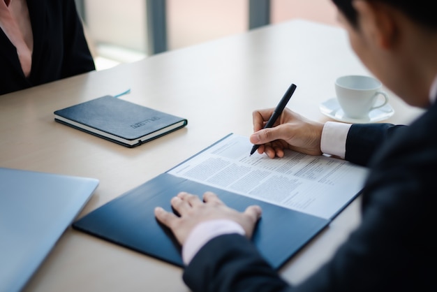 Photo gros plan de l'homme d'affaires écrivant ou signant un contrat sur papier au bureau.