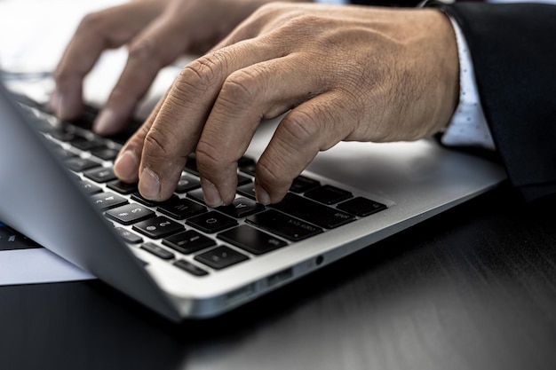 Gros plan Un homme d'affaires travaillant dans une salle privée, Il tape sur un clavier d'ordinateur portable, Il utilise un messager pour discuter avec un partenaire. Concept d'utilisation de la technologie dans la communication.