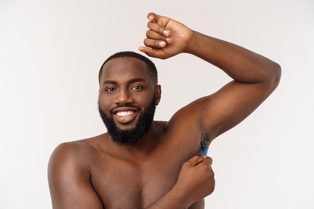 Gros plan d'un homme africain nu heureux se rasant avec un rasoir isolé sur fond gris