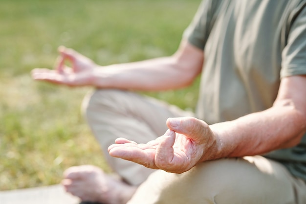 Gros plan d'un homme âgé assis en position du lotus et faisant du yoga