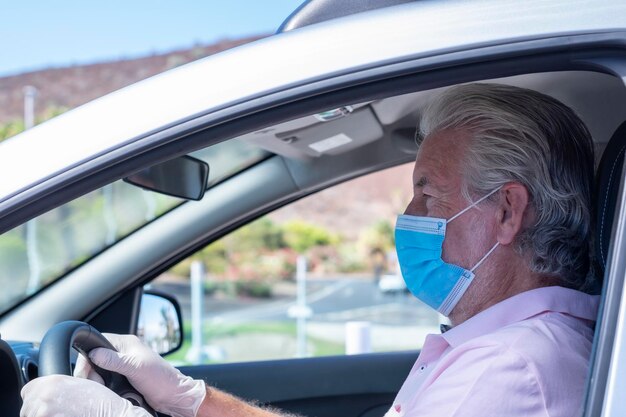 Un gros plan d'un homme âgé conduisant une voiture.
