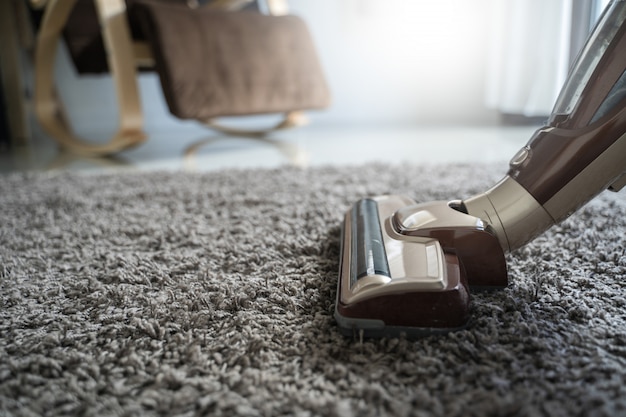 Gros plan homme à l'aide d'un aspirateur lors du nettoyage dans la chambre
