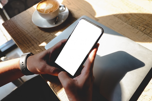 Gros plan de l'homme à l'aide de produits de commande de téléphone portable vierge pour faire du shopping en ligne dans le café.