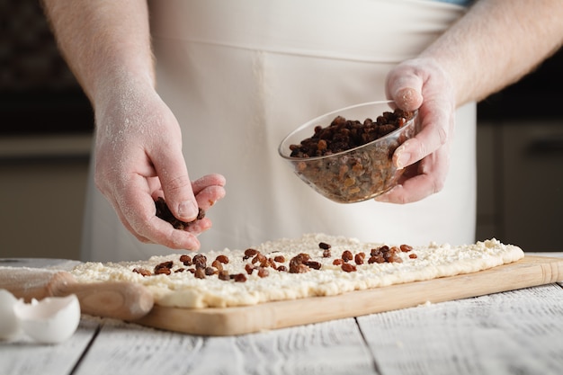 Gros plan de l'homme ajoute des raisins secs dans la pâte.