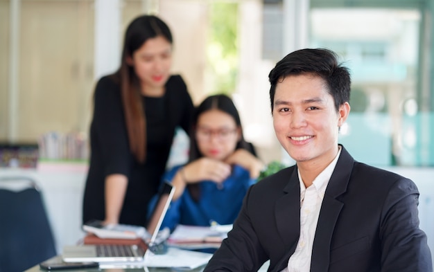 Gros plan sur l&#39;homme asiatique de gestionnaire en regardant la caméra et de travailler avec l&#39;équipe