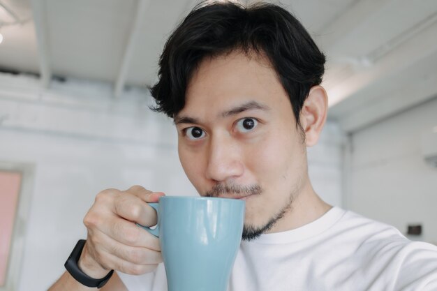 Gros plan d'un homme asiatique selfie lui-même boit du café chaud